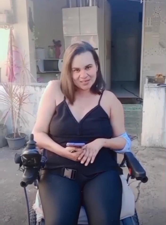 Clecia Lopes sorrindo em sua cadeira de rodas motorizada em Capim Grosso, Bahia.